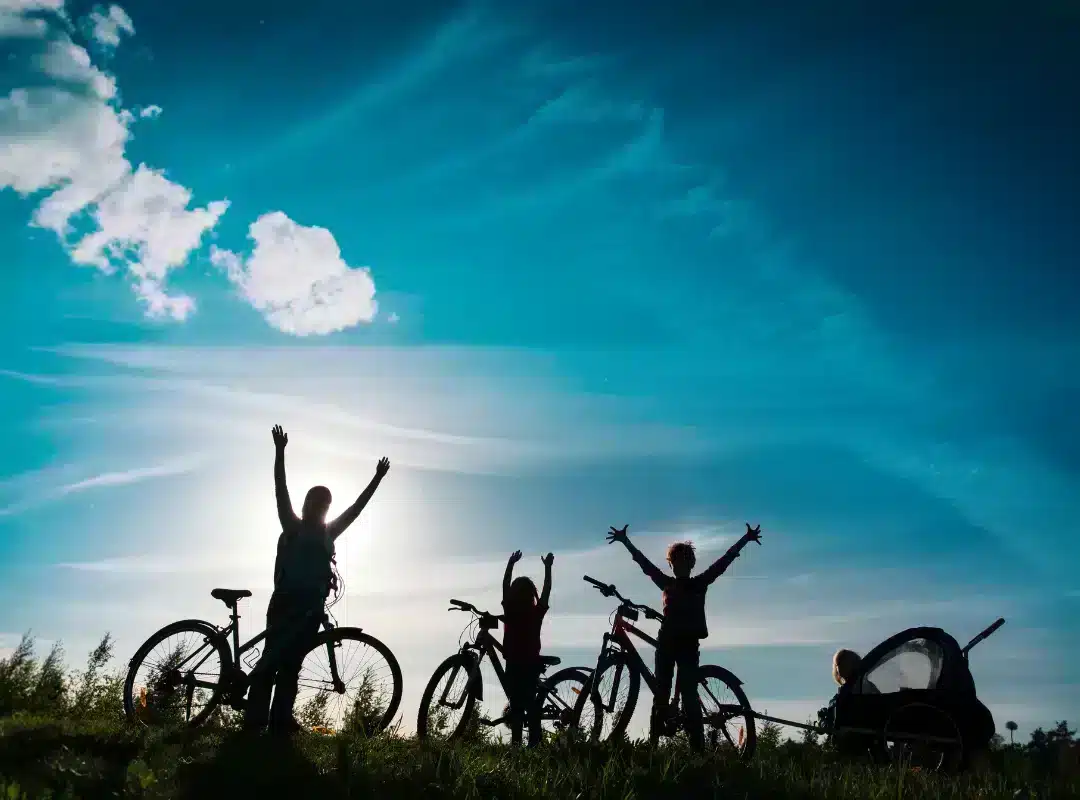 Voyager à vélo : comment bien se préparer ? 1 Famille à vélo sur une colline en contre jour